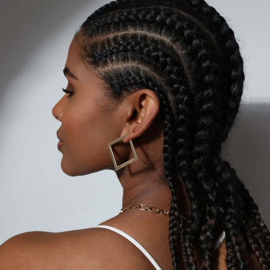 Femme avec des tresses africaines et boucles d'oreilles carrées.
