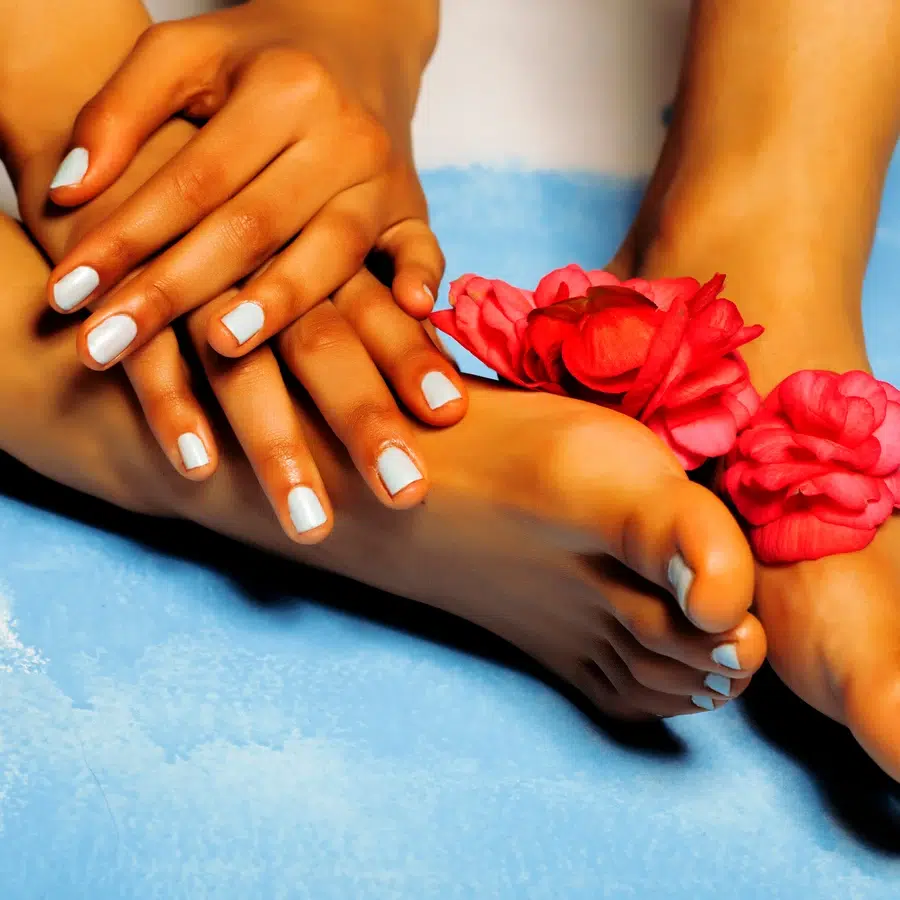 Mains et pieds avec vernis blanc et fleurs roses